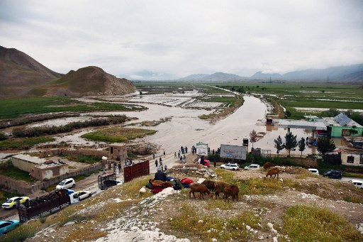 Warga berkumpul di sepanjang jalan di dekat daerah yang terendam banjir antara Samangan dan Mazar-i-Sharif menyusul hujan lebat di distrik Feroz Nakhchir, Provinsi Samangan, Afghanistan, Sabtu, 11 Mei 2024.