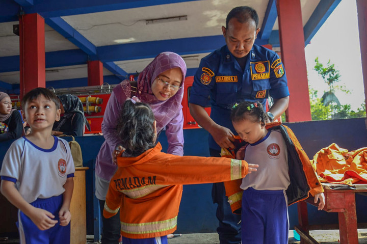 Petugas pemadam mendampingi siswa TK melakukan pelatihan pemadaman api saat kunjungan belajar ke markas pemadam kebakaran di Jalan Matraman Raya, Jakarta Timur, Rabu, 29 Mei 2024. 