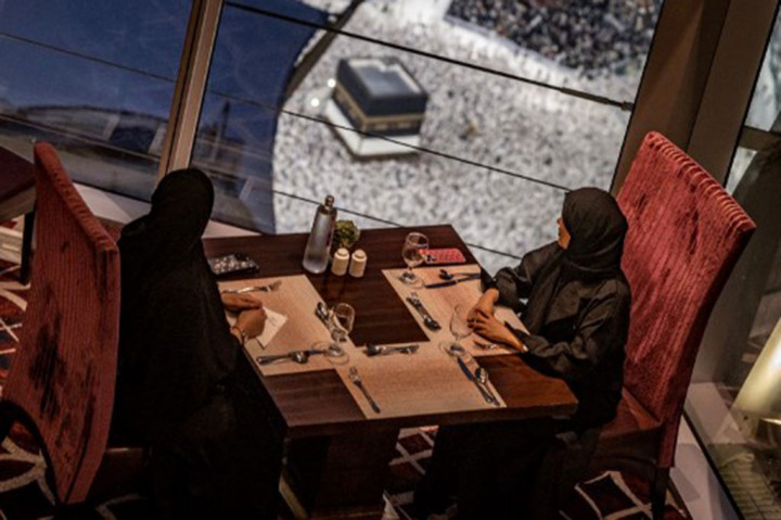 Dua perempuan duduk di sebuah restoran saat umat Muslim berjalan mengelilingi Ka'bah (tawaf), di Masjidil Haram, Mekah, Arab Saudi, Kamis, 13 Juni 2024, menjelang pelaksanaan ibadah haji.