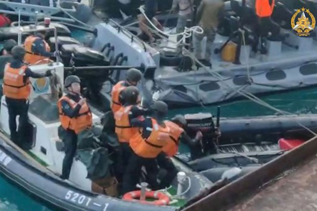 Gambar lain menunjukkan seorang anggota penjaga pantai Tiongkok (tengah) tampak mencoba menusuk perahu karet angkatan laut Filipina dengan senjata selama sebuah insiden lepas Second Thomas Shoal di Laut China Selatan.