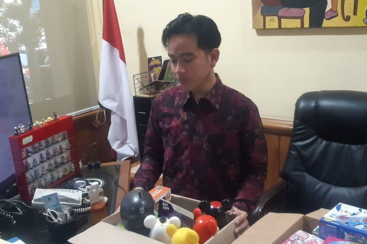 Tampak meja kerja Gibran penuh dengan tumpukan berkas dan sejumlah pajangan. Begitu sampai di ruangnya, ia langsung memasukkan beberapa pajangan yang ada diantaranya Lego, action figure, serta Tamiya.