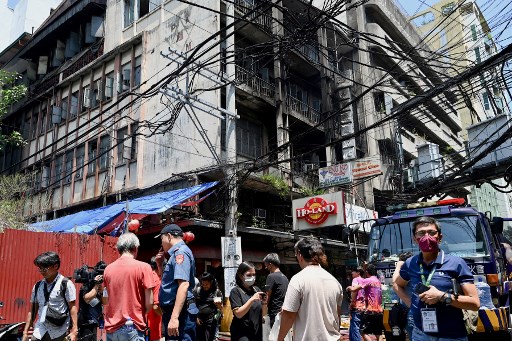 Polisi, warga dan awak media berada di lokasi kebakaran yang melanda sebuah gedung di Pecinan, Manila, Filipina, Jumat, 2 Agustus 2024. Sedikitnya 11 orang tewas akibat kejadian tersebut.