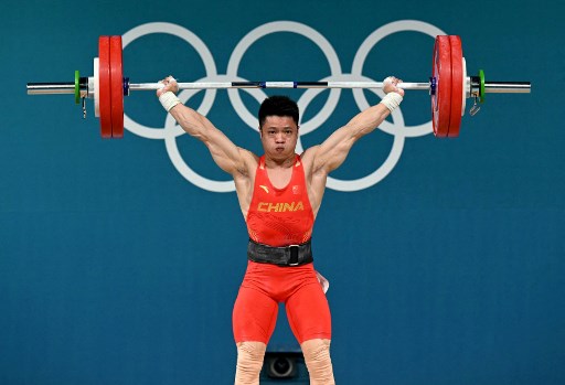 Atlet angkat besi asal Tiongkok Li Fabin memecahkan rekor angkatan snatch saat mengangkat beban seberat 148 kg pada laga angkat besi kelas 61 kg putra Olimpiade Paris 2024.