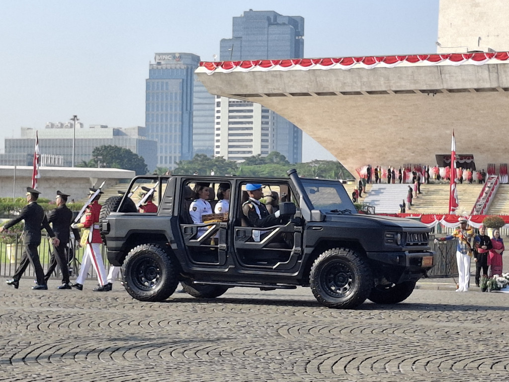 Personel Purna-Paskibraka Kachina Ozora dan Keyla Azzahra Purnama memangku replika bendera Merah Putih dan teks proklamasi di mobil Maung Pindad dalam prosesi kirab dari kawasan Monas menuju Lapangan Udara Halim Perdanakusuma.