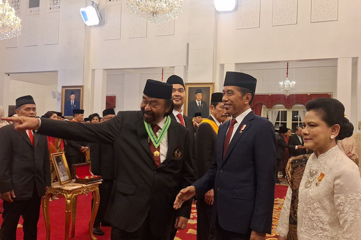 Presiden Jokowi juga merapikan posisi medali agar terlihat persisi. Peesiden juga menyematkan pin berwarna emas pada sisi kiri kantong jas Surya Paloh.