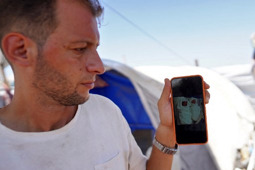 Mohammed Abu al-Qumsan menunjukkan foto anak kembarnya yang tewas akibat pengeboman Israel, saat ia berdiri di luar tenda di sebuah kamp pengungsi Palestina di Khan Yunis, di Jalur Gaza selatan pada Kamis, 15 Agustus 2024.