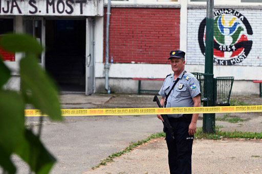 Seorang polisi berjaga-jaga di dekat sekolah menengah tempat tiga karyawan ditembak mati oleh seorang rekan kerja, yang kemudian mencoba bunuh diri, di Sanski Most, Bosnia barat laut, Rabu, 21 Agustus 2024.