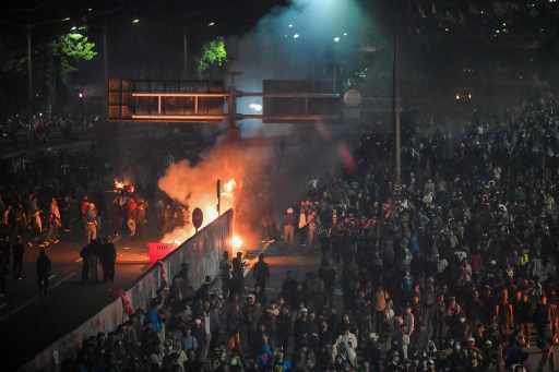 Saat dipadamkan menggunakan selang air pemadam kebakaran, massa mulai memanas dan melempari polisi.