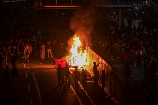 Api sempat membakar pagar bagian depan gedung DPR RI, Kamis, 22 Agustus 2024 malam. Petugas berusaha memadamkan api, namun dilemari massa demonstran dengan batu dan botol.