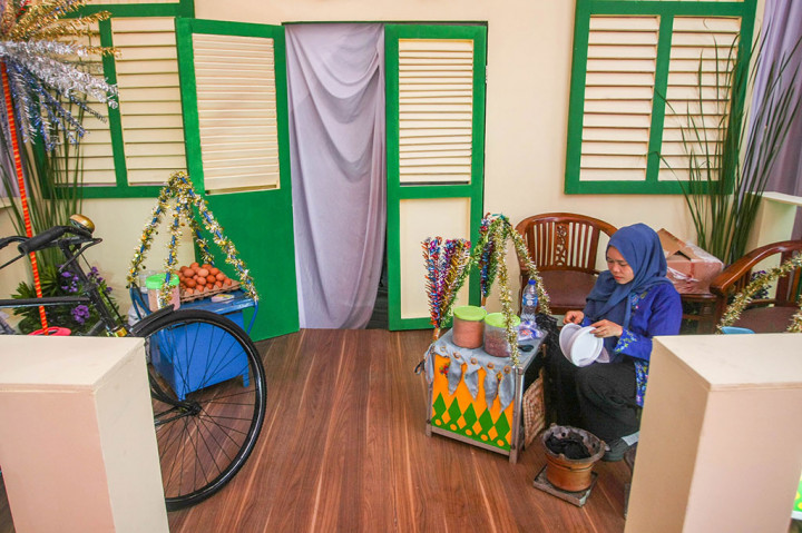 Di depan rumah Bapang juga terdapat miniatur Monas sebagai ikon kota DKI Jakarta. Kemudian, di samping juga ada pedagang kerak telor.