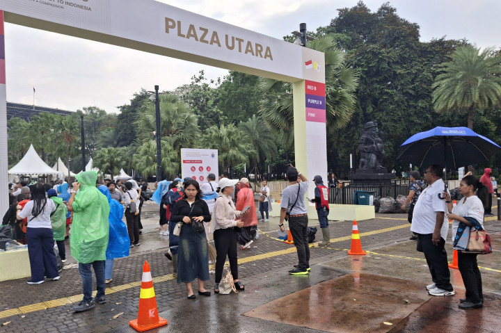 Dua tenda berwarna putih yang difungsikan sebagai pusat informasi mendadak dipenuhi peserta Misa Akbar. Beberapa dari mereka mencoba menerobos hujan berbekal jas hujan plastik.