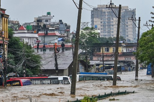 Warga memanjat atap rumah saat lingkungan mereka terendam banjir setelah Sungai Bagmati meluap menyusul hujan monsun lebat di Kathmandu, Nepal, Sabtu, 28 September 2024. 