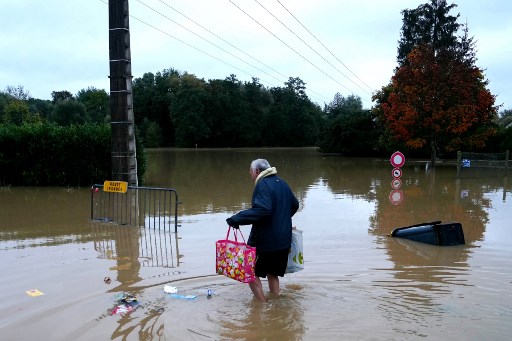 Seorang penduduk membawa tas berusaha mengarungi banjir di Pommeuse, departemen Seine-et-Marne, sebelah timur Paris, Kamis, 10 Oktober 2024, saat hujan lebat yang disebabkan badai Kirk berangsur-angsur mereda.