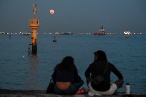 Orang-orang menyaksikan Hunter Moon yang muncul di langit Singapura, Kamis, 17 Oktober 2024.
