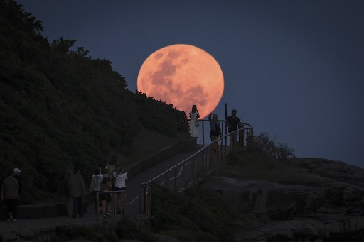 Hunter Moon muncul di belakang orang-orang yang berdiri di tanjung dekat Pantai Bondi, Sydney, Australia, Kamis, 17 Oktober 2024.