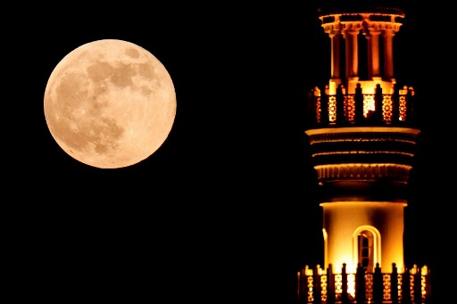 Bulan Purnama Sang Pemburu muncul di balik menara masjid di Doha, Qatar, Kamis, 17 Oktober 2024.