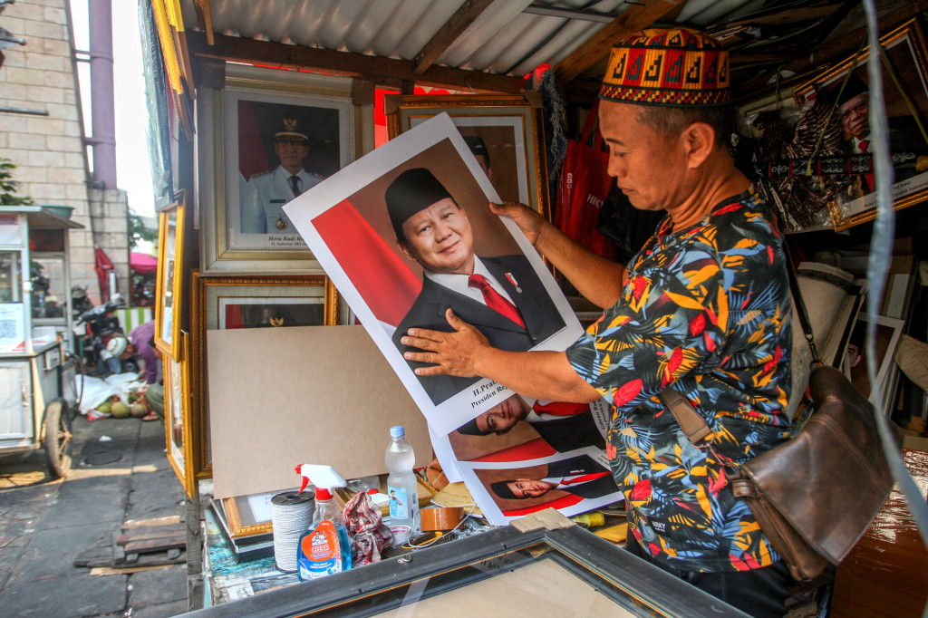 Perajin hendak memasang foto Presiden dan Wakil Presiden terpilih Prabowo Subianto dan Gibran Rakabuming Raka ke dalam pigura pesanan pelanggan di Pasar Baru, Jakarta Pusat, Jumat, 18 Oktober 2024. 