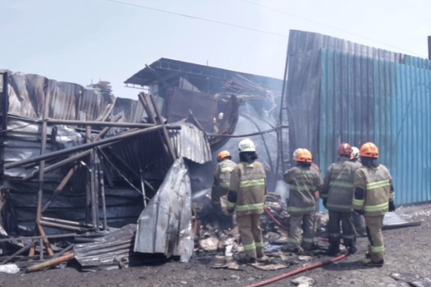 Kepulan asap hitam disertai kobaran api terus membesar dari lokasi gudang yang terbakar.