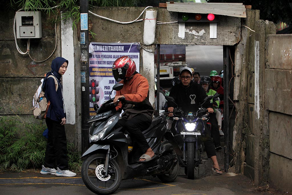 Pengurus lingkungan sekitar berinisiatif memasang rambu lalu-lintas untuk mengatur arus kelancaran kendaraan roda dua sekaligus menghindari keributan antarpengendara yang berebut masuk pintu Doraemon tersebut.