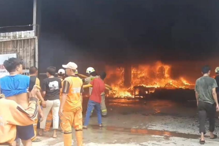 Asap hitam tebal tampak membumbung. Terlihat api berkobar menghanguskan bagian dalam gudang yang berada di lantai bawah.