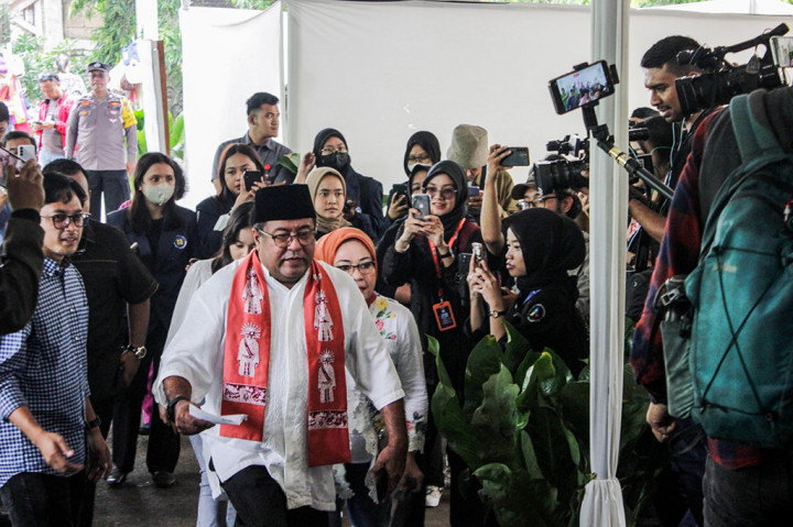 Pantauan Metrotvnews.com, Rano menggunakan baju koko berwarna putih berlengan pendek, celana serta kopiah hitam, dan sandal slop berwarna hitam, dilengkapi kain cukin warna oranye yang dikalungkan di lehernya. Rano ditemani istri Dewi Indriati dan seseorang cucu perempuan.