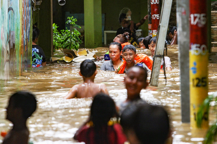 Warga beraktivitas di tengah banjir yang menggenangi kawasan pemukiman padat penduduk di Kebon Pala, Kampung Melayu, Jakarta Timur, Kamis, 28 November 2024.
