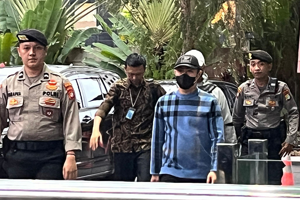 Risnandar menggunakan baju biru lengan panjang bercorak garis hitam saat tiba di Gedung Merah Putih KPK. Dia menutup wajahnya dengan topi dan masker berwarna hitam.