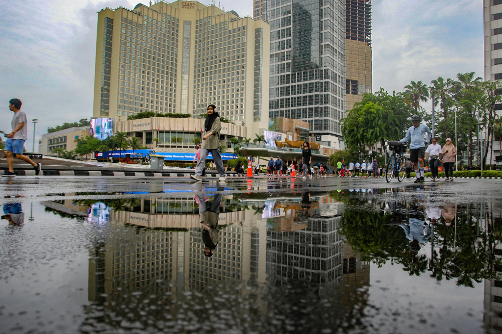 Warga melakukan aktivitas olahraga di arena CFD kawasan Jalan Thamrin yang tergenang air, Jakarta, Minggu, 8 Desember 2024. 