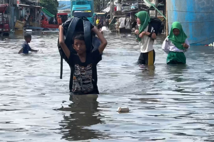 Tampak di lokasi sejumlah pelajar SD terpaksa menerobos banjir usai pulang dari sekolahnya. Begitu juga satu keluarga yang terpaksa menerobos dengan menggendong anaknya yang masih bayi.