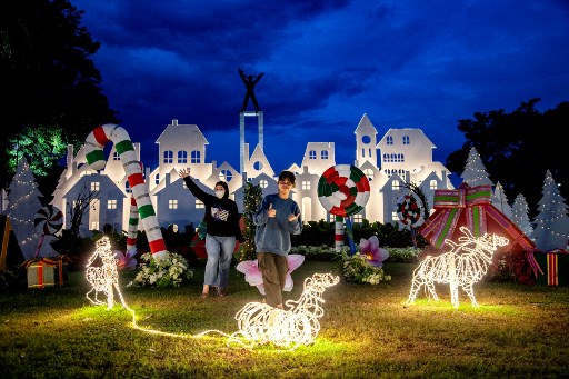 Warga berforo dengan latar belakang dekorasi Natal di Taman Lapangan Banteng, Jakarta, Selasa, 24 Desember 2024. 