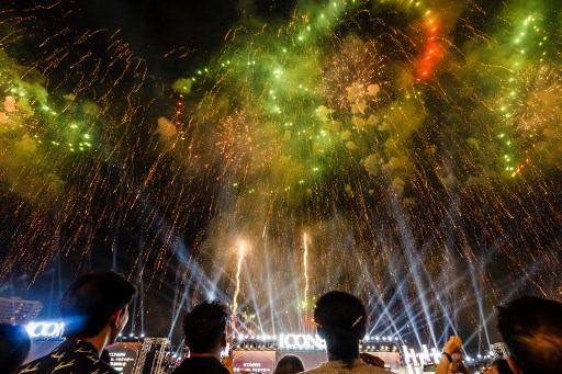 Orang-orang menyaksikan kembang api menerangi langit selama perayaan Malam Tahun Baru di ICONSIAM di Bangkok pada tanggal 1 Januari 2024. AFP PHOTO/Chanakarn Laosarakham