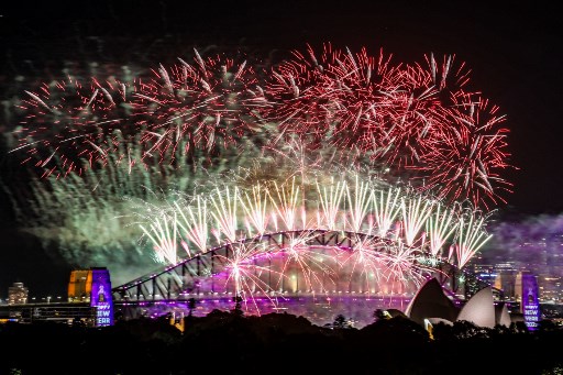 Kembang api menerangi langit tengah malam di atas Jembatan Pelabuhan Sydney dan Gedung Opera Sydney selama perayaan Hari Tahun Baru 2025 di Sydney. AFP PHOTO/David Gray