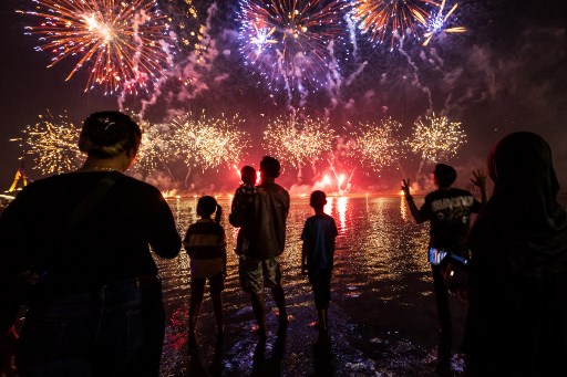 Warga setempat menyaksikan kembang api saat merayakan Tahun Baru di Pantai Ancol, Jakarta, pada 1 Januari 2025. AFP PHOTO/Yasuyoshi Chiba