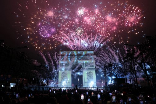Kembang api menerangi langit di sekitar Arc de Triomphe di Avenue des Champs-Elysees di Paris selama perayaan Tahun Baru. AFP PHOTO/Thomas Samson