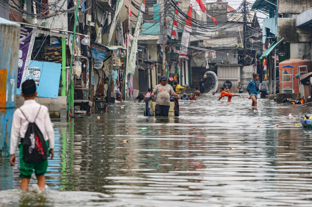 Warga melintasi banjir rob yang menggenangi kawasan Muara Angke, Jakarta Utara, Selasa, 14 Januari 2025.
