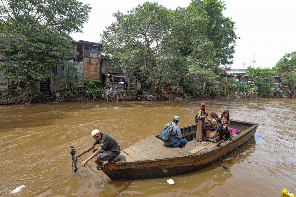 Pelajar menaiki perahu eretan untuk menyeberangi Sungai Ciliwung di kawasan Manggarai, Jakarta Selatan, Rabu, 15 Januari 2025. 