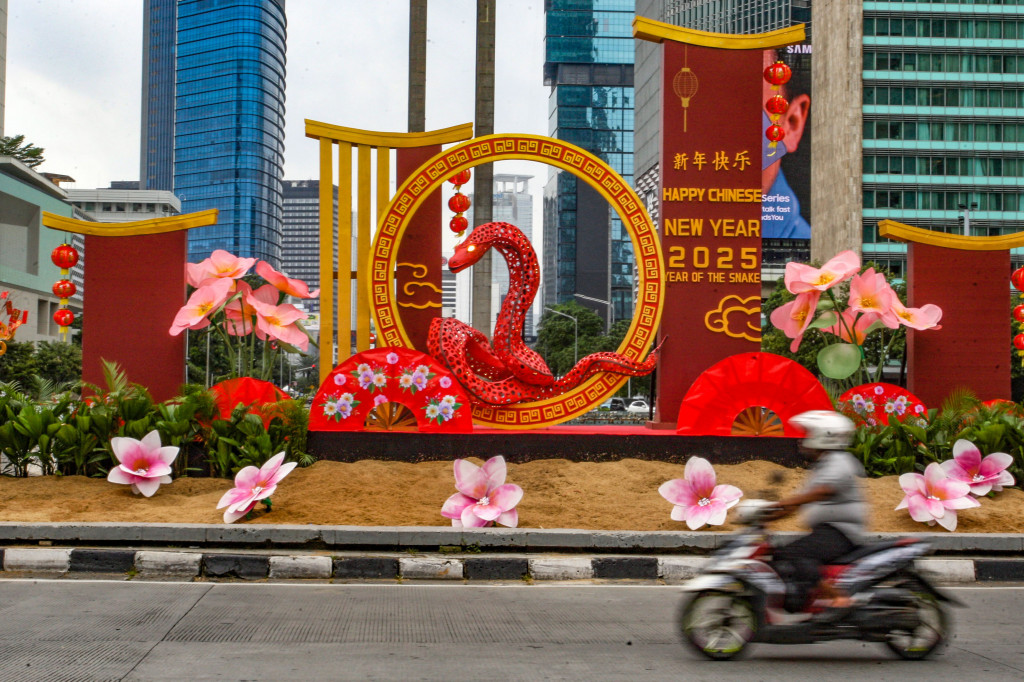 Kendaraan melintas di dekat dekorasi Imlek berbentuk Shio Ular Kayu di Bundaran HI, Jakarta, Senin, 27 Januari 2025. 