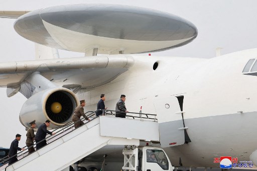 Foto-foto yang dipublikasikan oleh media pemerintah menunjukkan Kim menaiki tangga menuju pintu sebuah pesawat besar dengan empat mesin dan kubah radar yang dipasang di badan pesawat, dan melihat pesawat itu terbang rendah.