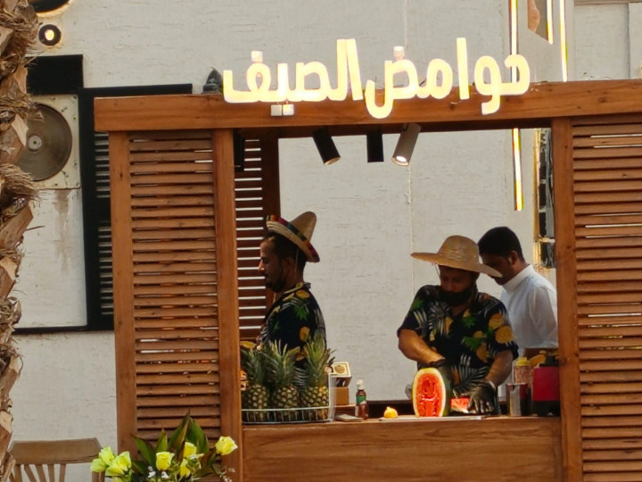 Seorang pramusaji cafe dengan pakaian khas Hawai tengah melayani pelanggan yang ingin menikmati kudapan