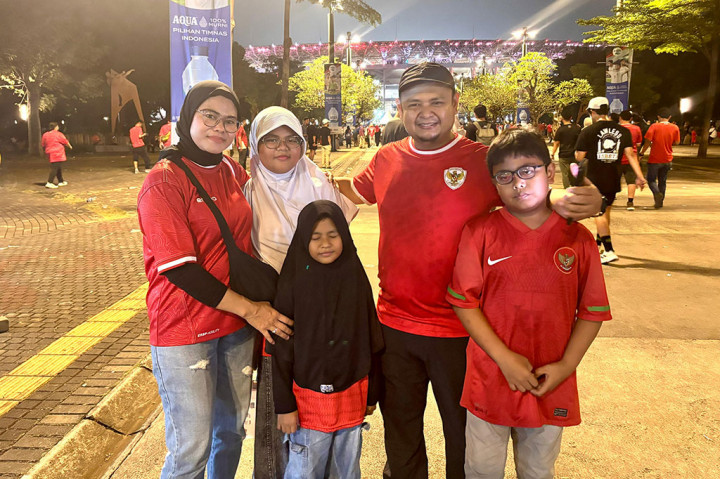 Sebuah keluarga suporter Timnas Indonesia berfoto bersama sebelum memasuki stadion. Mereka kompak mengenakan jersey merah kebanggaan sebagai bentuk dukungan untuk skuad Garuda.