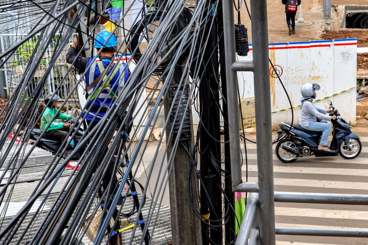 Seorang pekerja terlihat sedang melakukan perbaikan pada instalasi jaringan kabel udara yang tampak semrawut di kawasan Jalan Saharjo, Jakarta Selatan, Kamis, 14 Agustus 2025. 