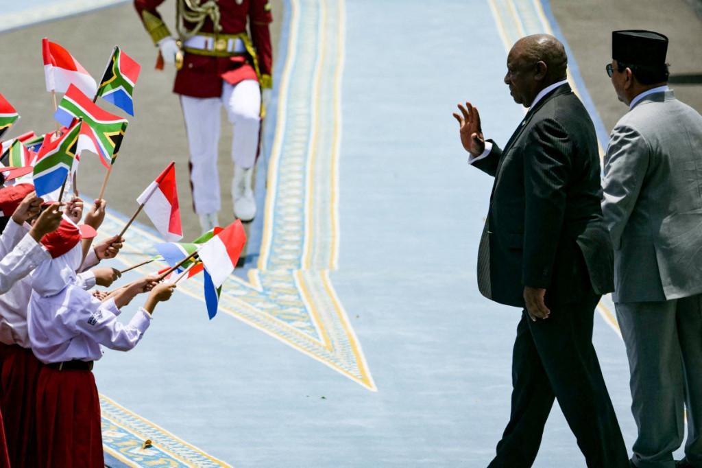 Para pelajar dengan antusias mengibarkan bendera Indonesia dan Afrika Selatan, yang menambah semarak suasana penyambutan iring-iringan kendaraan Presiden Ramaphosa.