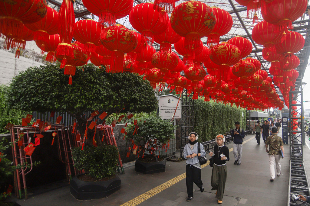 Pedestrian melewati trotoar yang dihiasi lampion dan ornament Imlek jelang Jakarta Light Festival bertema Imlek di Kawasan Bundaran HI, Thamrin, Jakarta, Rabu, 11 Februari 2026. 