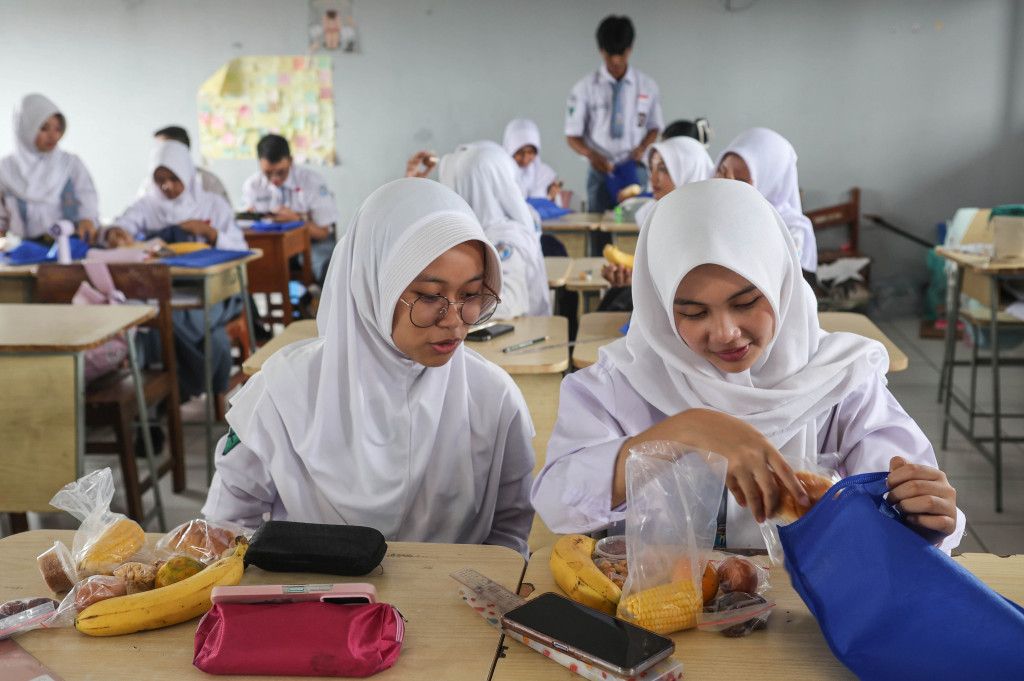 Siswa membuka isi paket Makan Bergizi Gratis (MBG) Ramadan yang diberikan sekaligus untuk tiga hari ke depan, sebelum dipindahkan ke dalam wadah yang disiapkan mandiri untuk dibawa pulang, di SMA Negeri 5 Kota Tangerang Selatan, Banten, Senin, 2 Maret 2026.