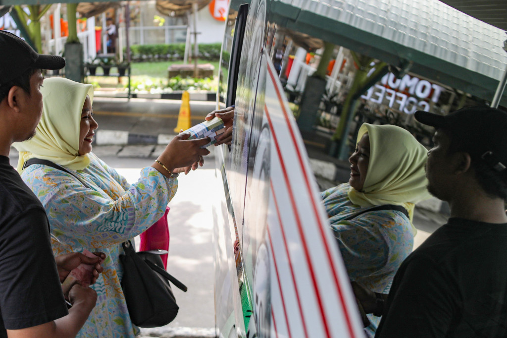 Warga antre untuk menukarkan uang baru yang disediakan oleh Bank Indonesia di area parkir Stasiun Gambir, Jakarta, Senin, 16 Maret 2026. 
