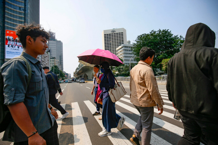 Pejalan kaki menggunakan payung untuk melindungi diri dari cuaca terik di kawasan Tosari, Jakarta, Senin (27/4/2026).