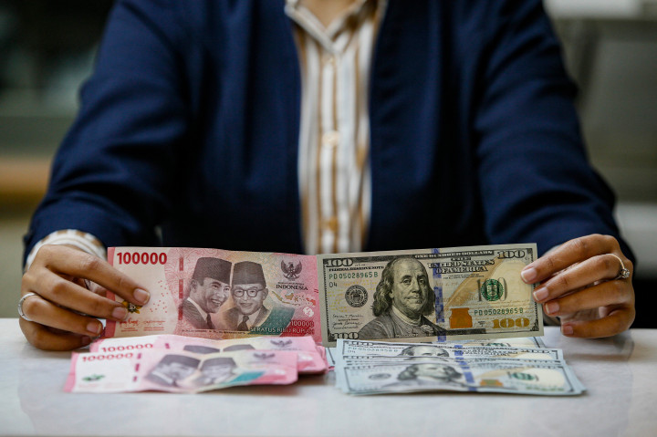 Karyawan menunjukkan uang pecahan dolar Amerika Serikat (AS) dan rupiah di gerai penukaran mata uang asing di Jakarta, Selasa, 5 Mei 2026. 