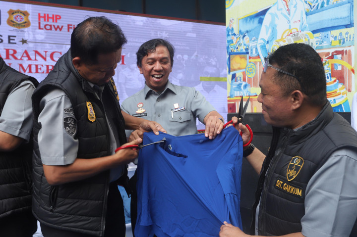 Petugas Dit Gakkum Kementerian Hukum, menggunting pakaian bermerk Lacoste tiruan di Jakarta, Senin, 22 Juni 2026. 
