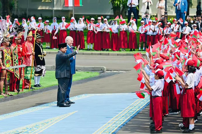 Setibanya di halaman Istana Merdeka, tampak ratusan siswa sekolah dasar berdiri berjajar dengan melambaikan bendera kedua negara. 