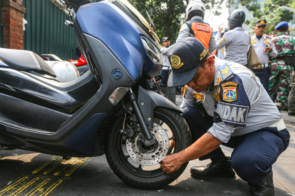 Petugas gabungan menderek mobil yang parkir di bahu jalan dan menutup trotoar di kawasan Senopati, Jakarta, Senin, 28 September 2026.